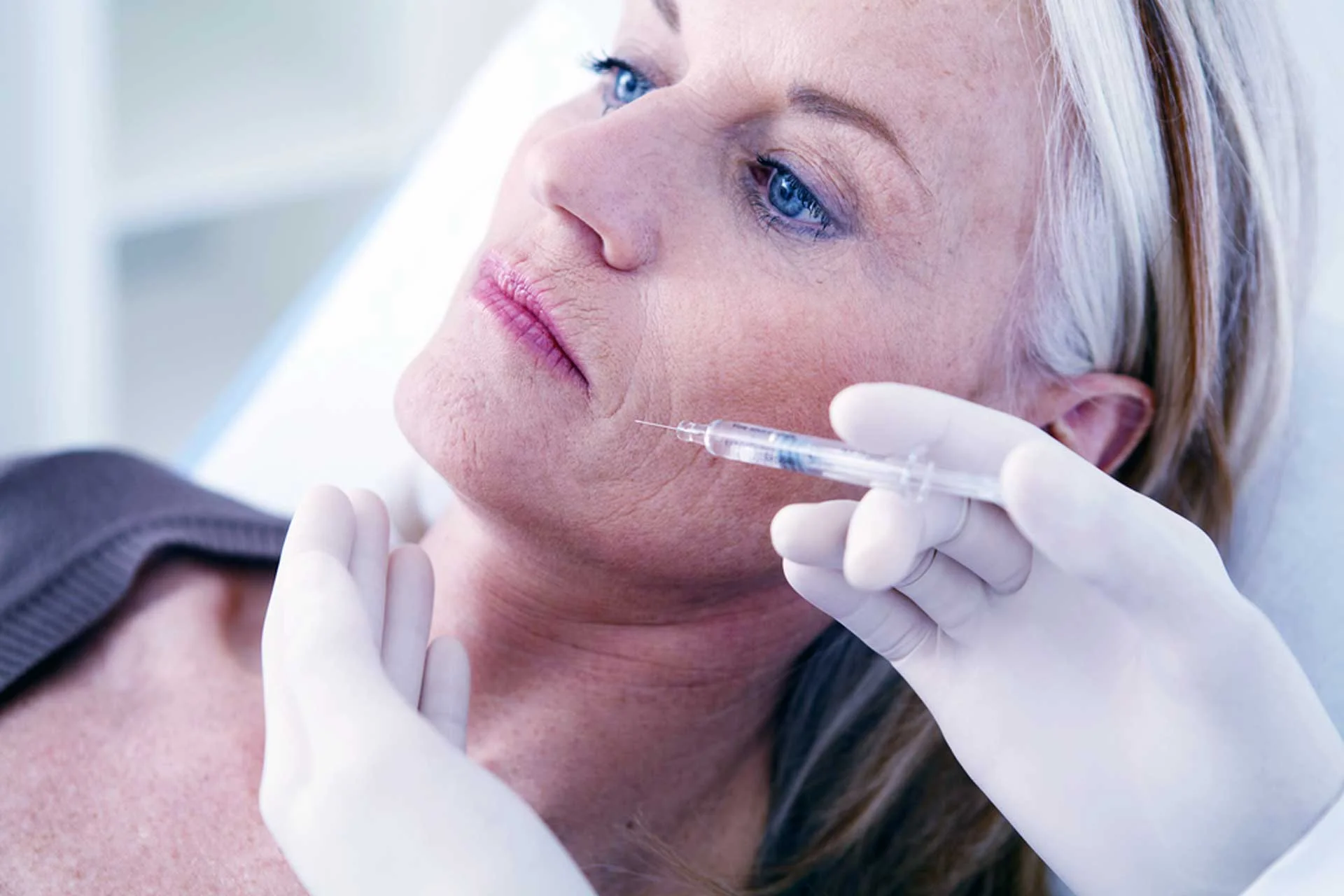 Natürliche Resultate: Ein Hautarzt injiziert Botox und injizierbare Füllmaterialien zur Faltenbehandlung im Gesicht einer Patientin.